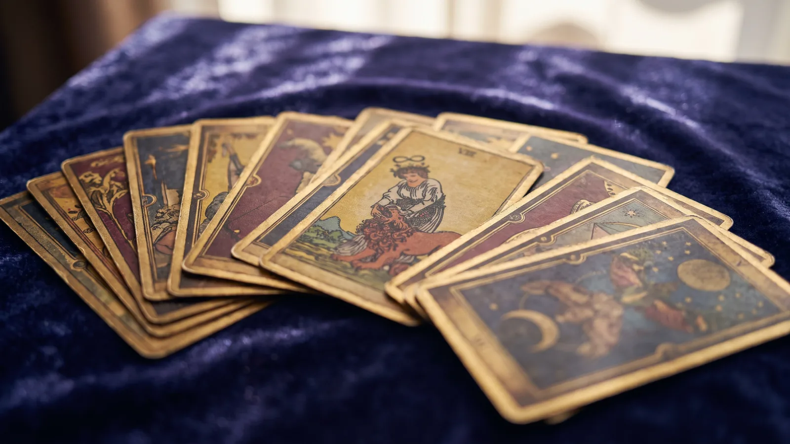 Jeu de cartes de tarot et d'oracle étalé en éventail sur un tissu de velours bleu